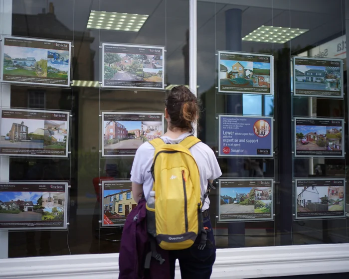 A prospective buyer looking at property listings in an estate agent's window