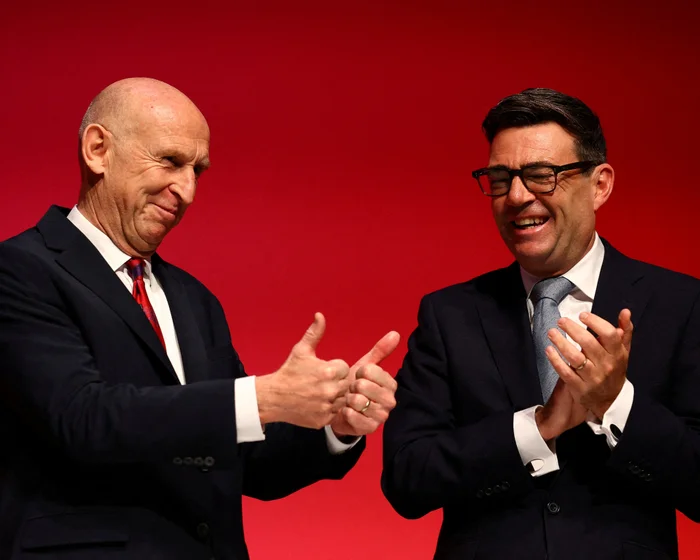 Andy Burnham and John Healey laughing and gesturing together on a conference stage