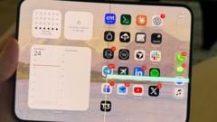 An Apple iPhone Duo foldable smartphone open on a flat surface showing a crack along the inner display crease