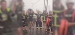 Indonesian firefighters in protective uniforms celebrating and praying in heavy rain during wildfire operations