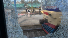 Emergency responders carry an injured person beside a damaged passenger train at Dnipro railway station.