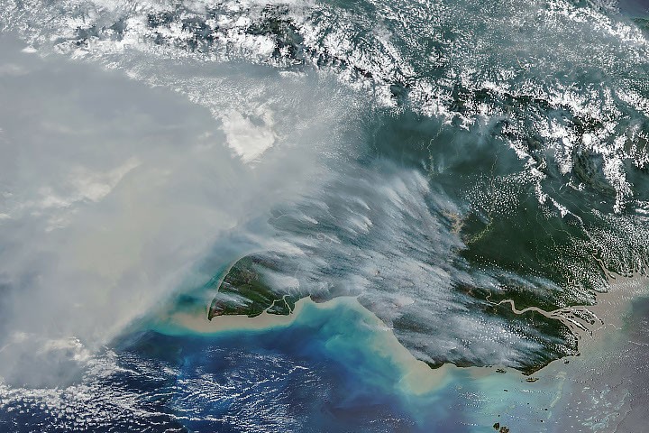 Satellite imagery from NOAA-20 showing dense plumes of smoke rising from fires across southern New Guinea.