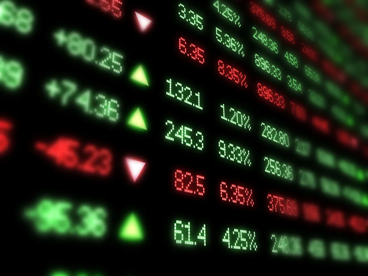 Wall Street stock market trading board displaying declining financial index numbers against an illuminated digital backdrop