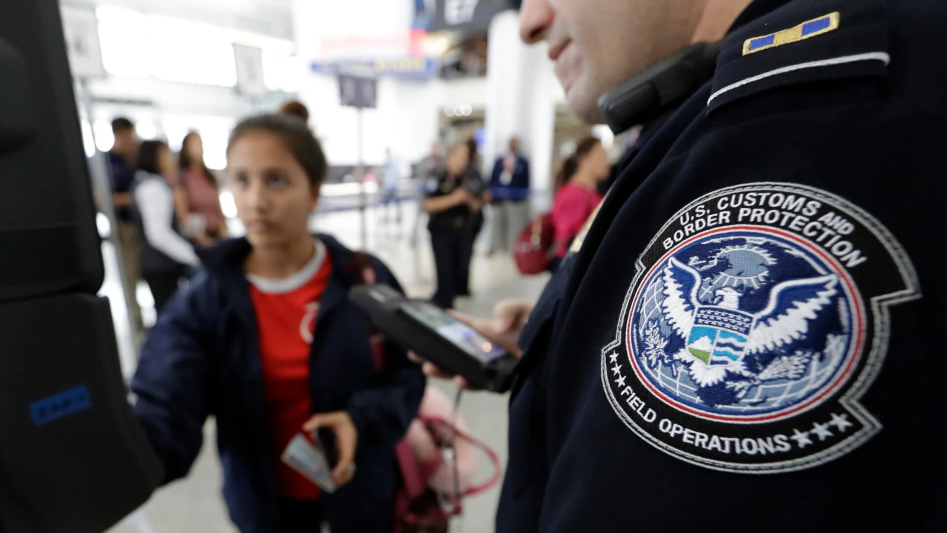 A traveler places an electronic device and smartphone in an inspection tray at an airport security checkpoint.
