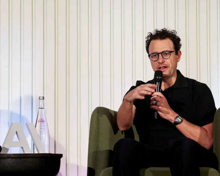 Anthropic CEO Dario Amodei speaking into a microphone while seated onstage