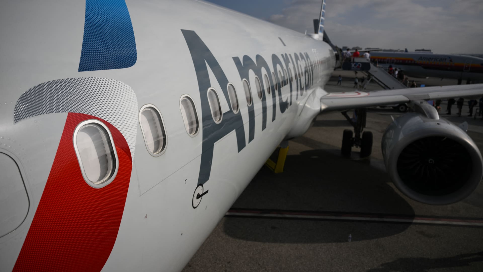 An American Airlines commercial jet airliner preparing for takeoff on an airport runway under clear skies.