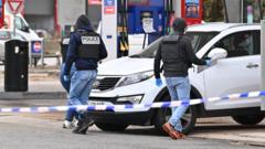 Forensic officers examine evidence at a petrol station in Trappes following the shooting.