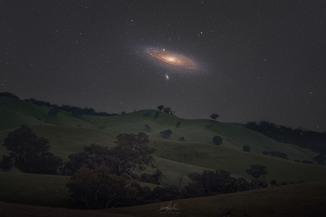 The Andromeda Galaxy glows across the night sky hovering just above rolling dark hills in rural New South Wales, Australia.