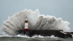 Waves crashing against a coastal barrier and seafront in the south of the UK during severe storm conditions