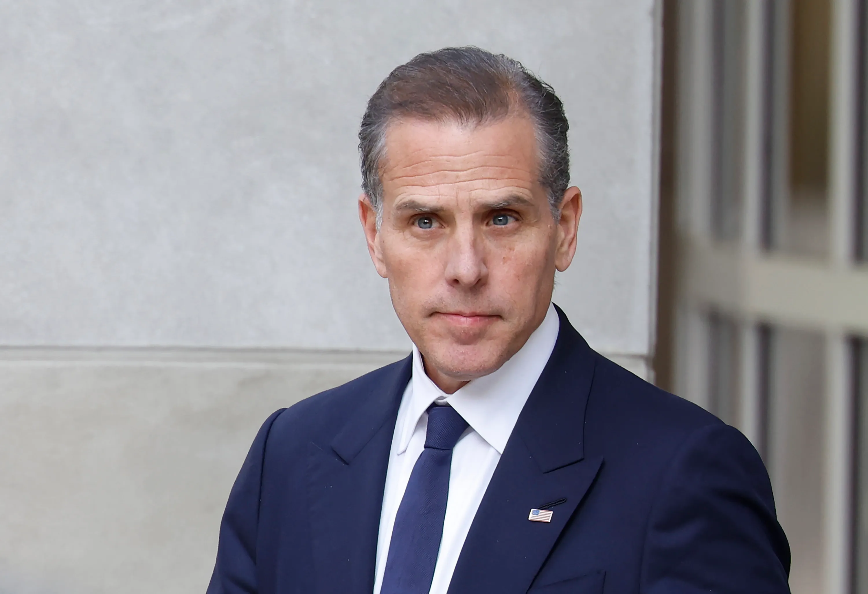 Hunter Biden attending a public event in a dark suit with a neutral background.
