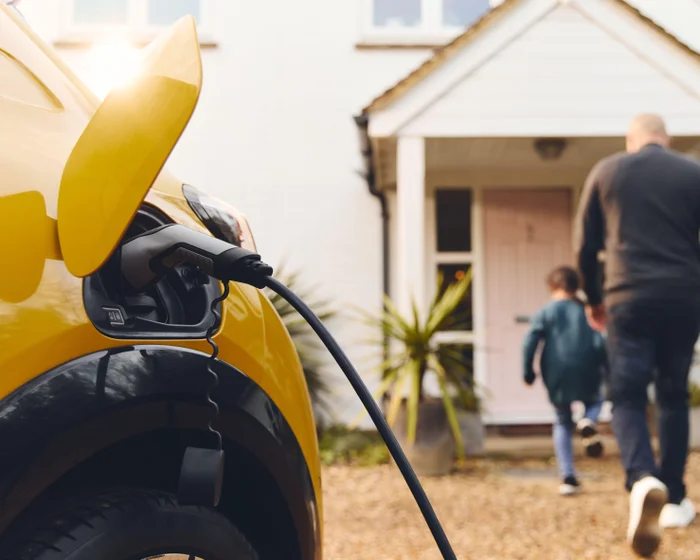 An electric car connected to a charging point on a residential driveway